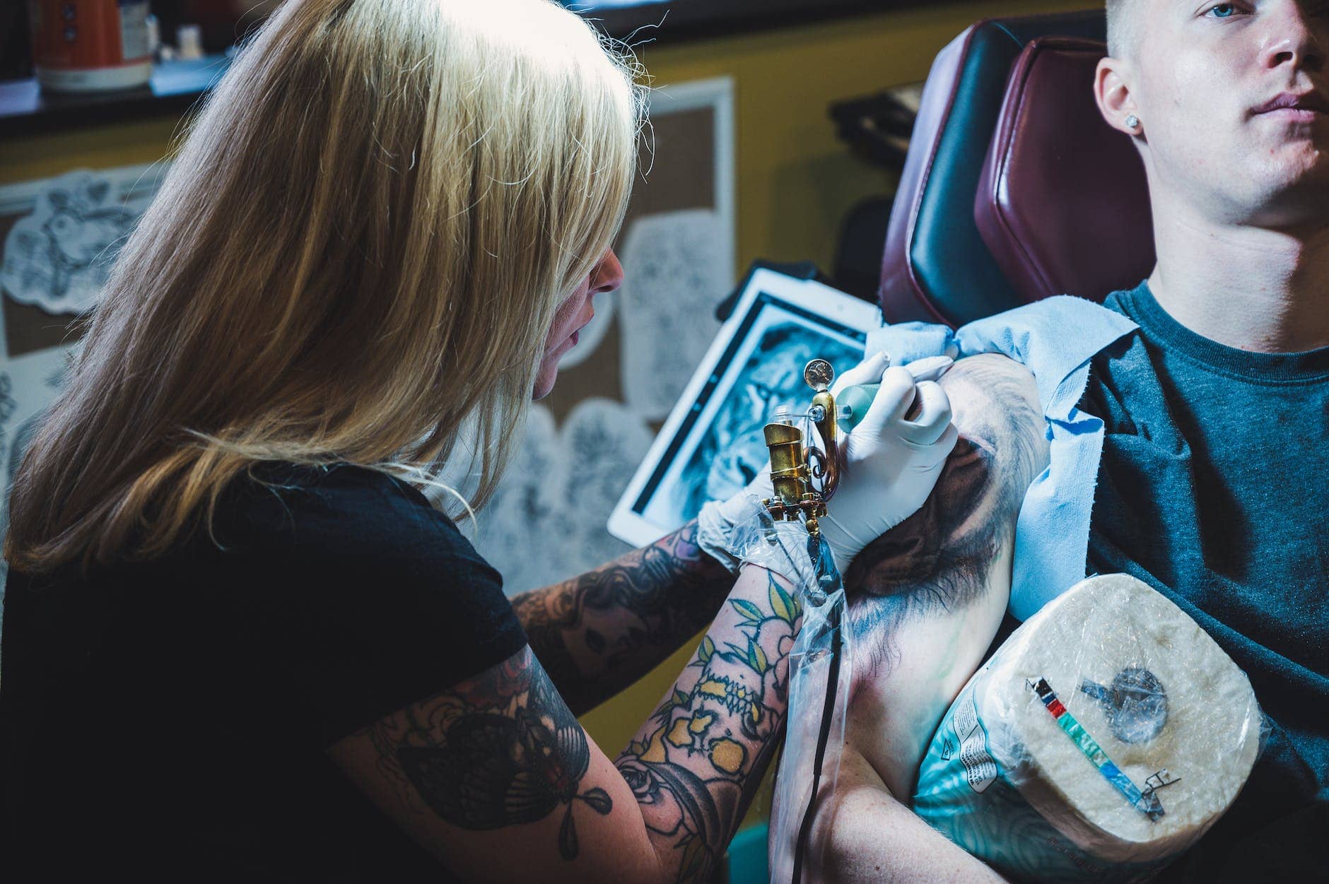woman tattooing man on his right arm